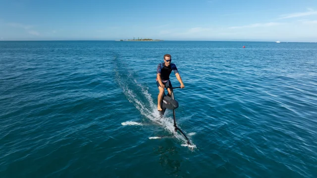 Homme pratiquant de l'hydrofoiler sur l'océan avec l'ilot canard au loin en Nouvelle-Calédonie